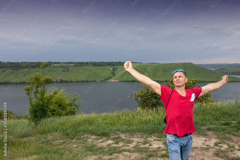 Handsome happy man with raised hands posing near pond in summer day Handsome happy man with raised hands posing near pond in summer day