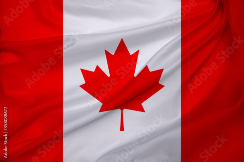 photo of the beautiful colored national flag of the modern state of Canada on textured fabric, concept of tourism, emigration, economics and politics, closeup