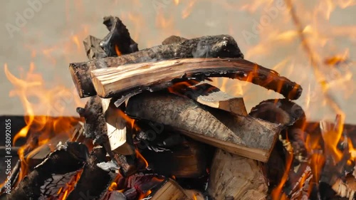 Birch firewood burns in a barbecue grill. Sunny spring day. Nobody. Picnic on a site near the house. Charcoal fire barbecue