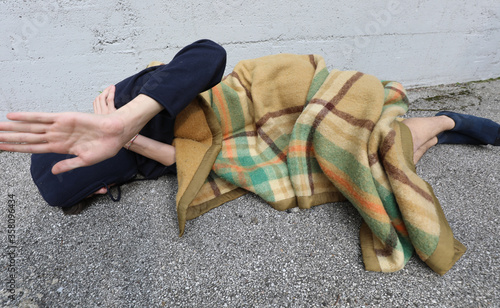 annoyed homeless young man raises his hand from under a filthy b photo