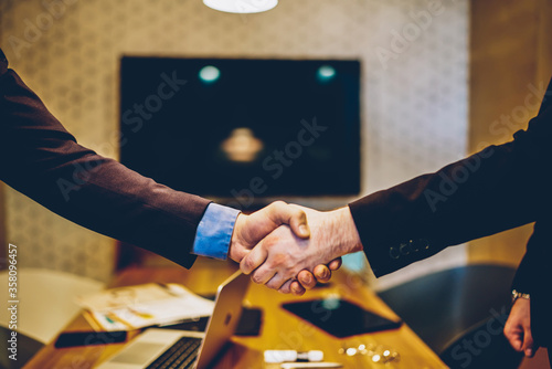 Cropped image of male's hands shaking in sign of making profitable deal for common business project,man agree in strategy of cooperation making contract for partnership in office during meeting