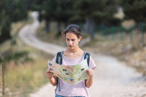 Lost hiker looking at a map while walking in the woods