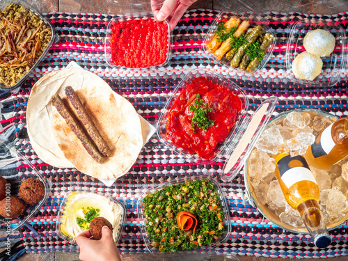 Two People are Sharing a Lebanese Arabic Picnic with Shawarma, Eggplants, Hummus, Tabouleh, Lentil Rice, Kibe, Falafel, Stuffed Vine Leafs and Cold Beers in Ice Bucket
