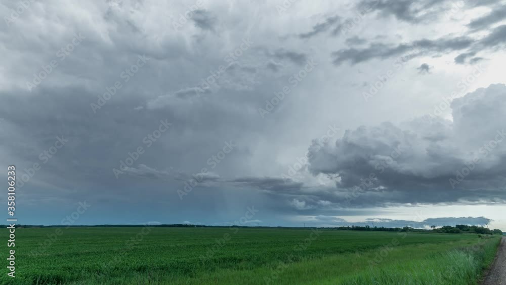 Time lapse of a thunderstorm clouds with a small lightning strike over a prairie setting with gravel road on the right side. Clouds moving from behind. Time lapse of a thunderstorm clouds with a small lightning strike over a prairie setting with gravel road on the right side. Clouds moving from behind.