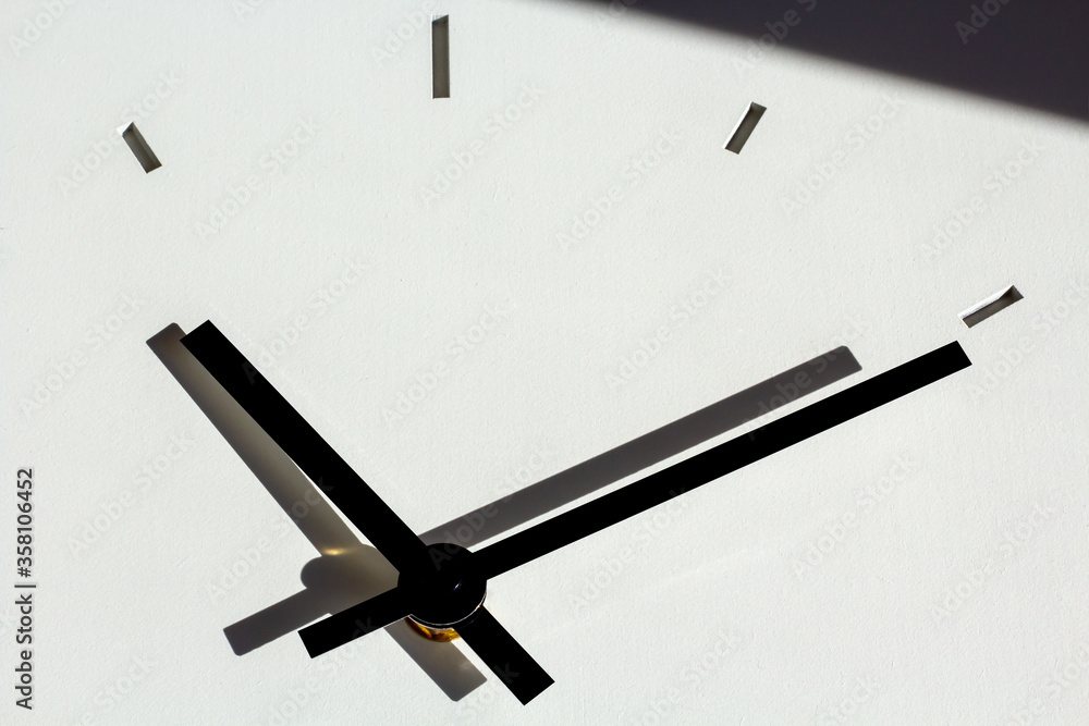 hands of a wall clock, with shadows on white, cementitious background ...