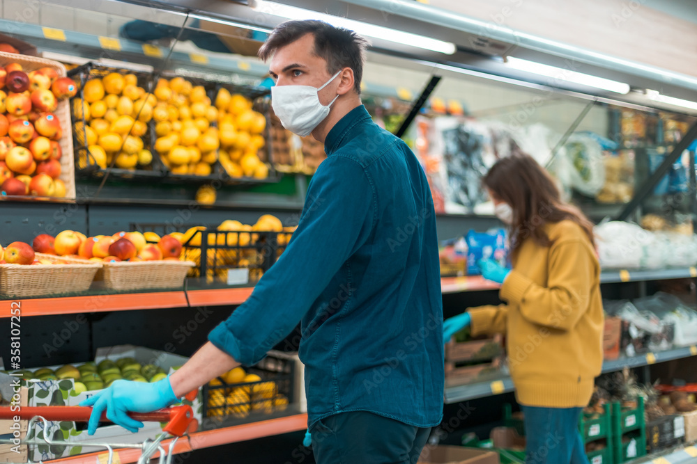 shoppers in protective masks choosing fruit in the supermarket