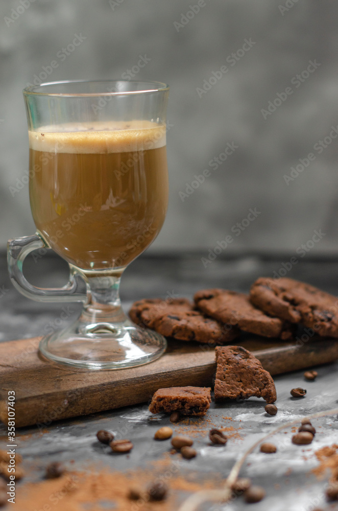 a cookie with pieces of chocolate tied with a string lies on a wooden board and next to a cup of latte a cookie with pieces of chocolate tied with a string lies on a wooden board and next to a cup of latte