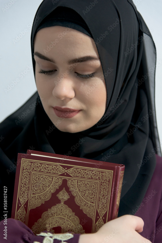 a young beautiful Muslim woman with hijab in the holy month of Ramadan embraces and learns the Qur'an a young beautiful Muslim woman with hijab in the holy month of Ramadan embraces and learns the Qur'an
