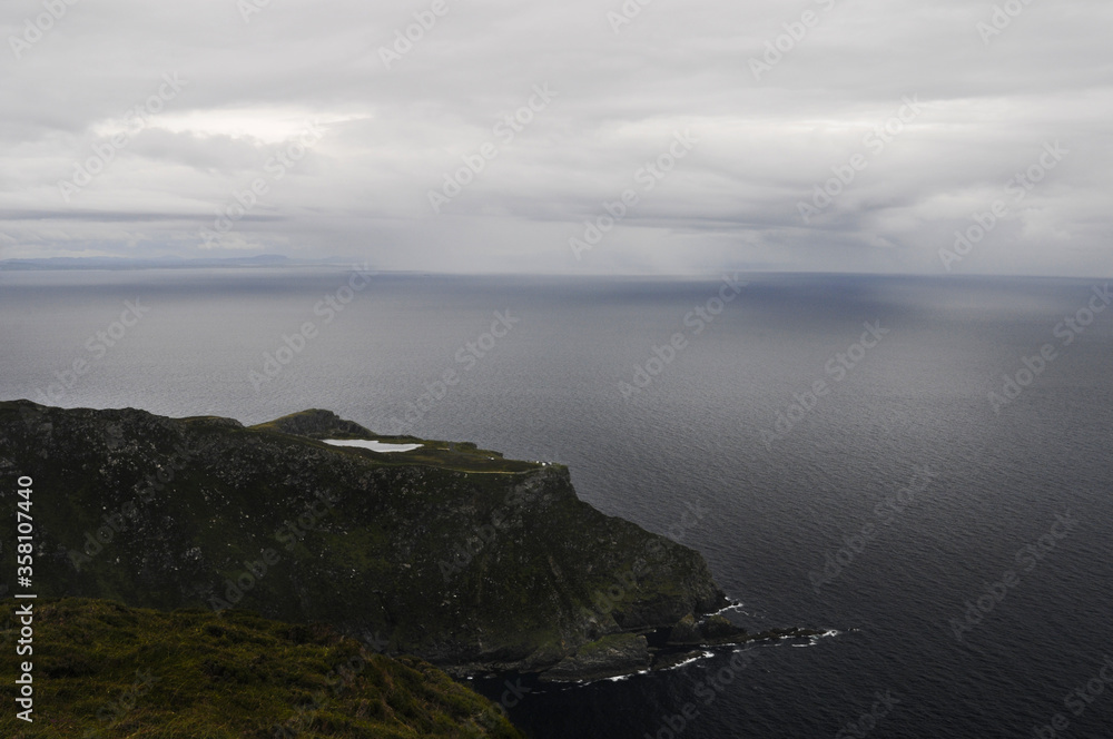 Vue sur la mer et un orage, la pluie tombant sous un nuage à l'horizon depuis les falaises au nord de l'Irlande.