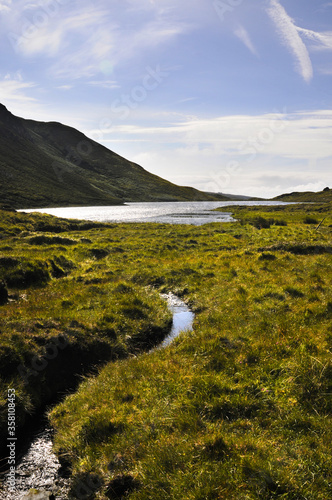 Petit lac de montagne en Irlande se déversant un un fin ruisseau se transformant en rivière et se jetant dans la mer en contrebas.