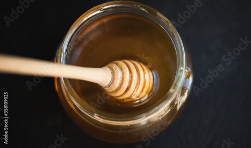 Honey and honey spoon on a light background. Sweet honey in the jar, place for text. 