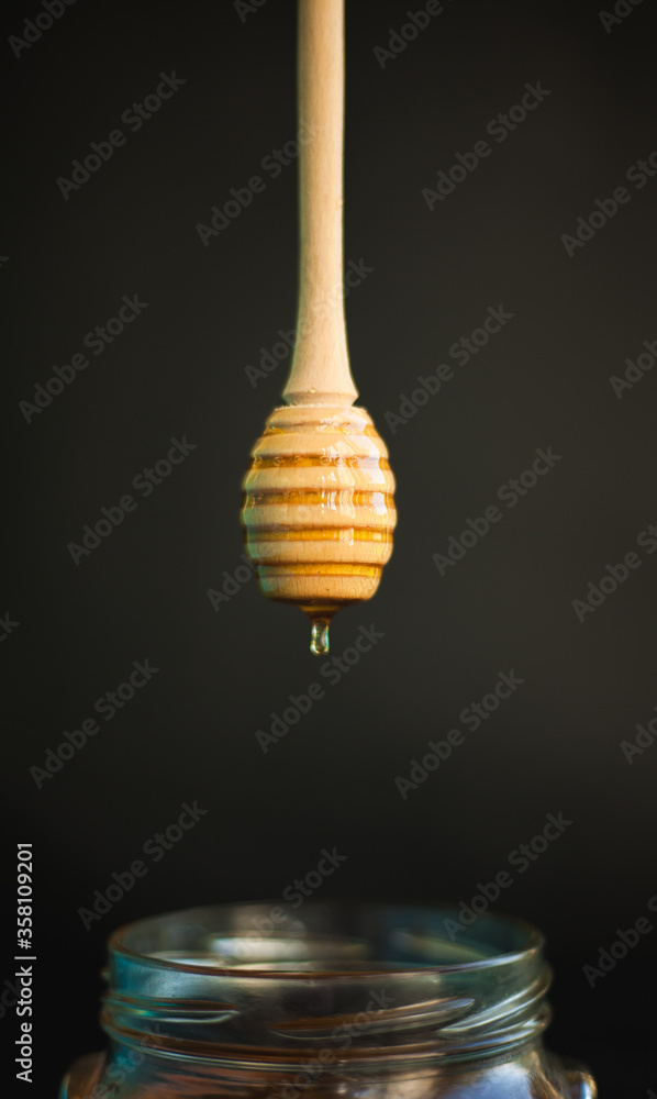 Honey and honey spoon on a light background. Sweet honey in the jar, place for text.
