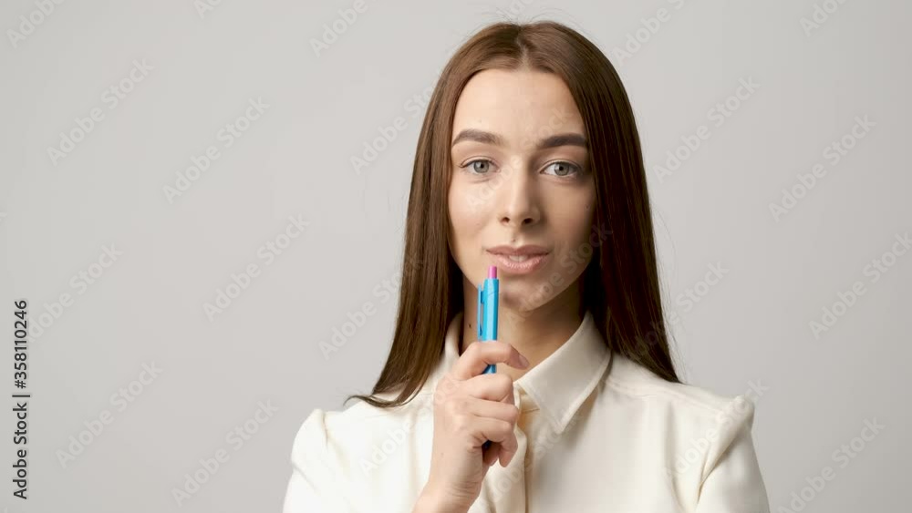 Portrait of a young lawyer standing in the office smiling with a pen in his hands on a white wall background Portrait of a young lawyer standing in the office smiling with a pen in his hands on a white wall background