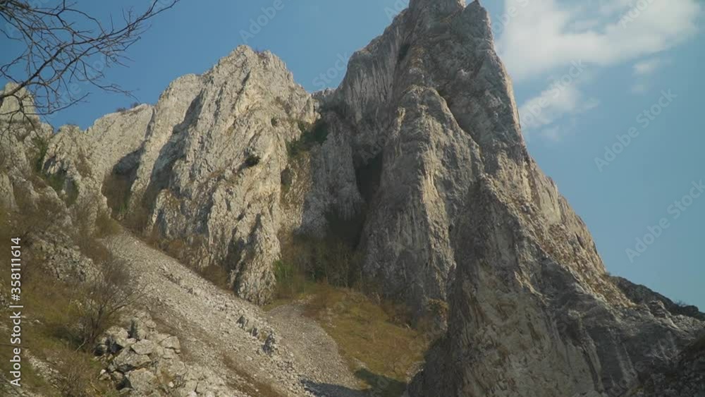Climbers Hike Towards Steep Mountain - Via Ferrata - Tilt up wide shot Climbers Hike Towards Steep Mountain - Via Ferrata - Tilt up wide shot