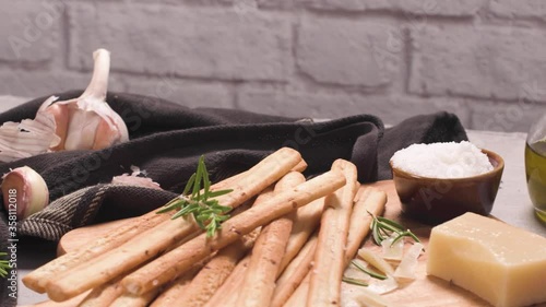 Fresh baked homemade grissini bread sticks in vintage metal grid box with olive oil and rosemary herbs over kitchen counter top. photo