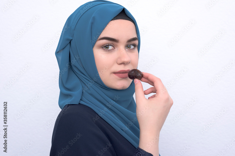 portrait of a beautiful Muslim woman with a hijab on a black background holds dates in her hands in the holy month of Ramadan. portrait of a beautiful Muslim woman with a hijab on a black background holds dates in her hands in the holy month of Ramadan.