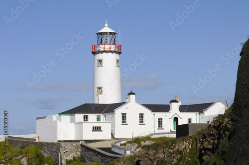 Magnifique phare blanc pos   sur des falaises rocheuses et verdoyantes au bord de la mer bleu indigo de l Irlande du nord.