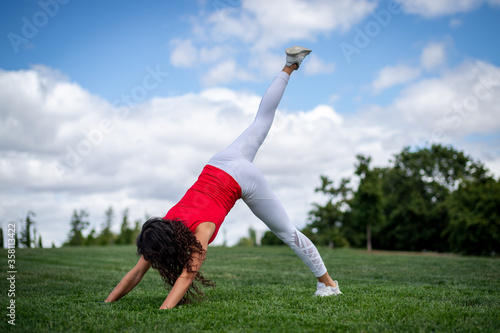 Young pretty fitness woman doing yoga postures in a park on the grass with white clothes