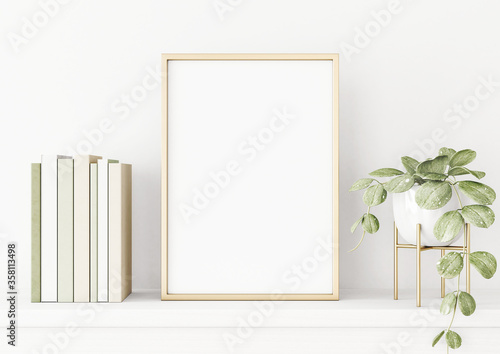 Poster mockup with vertical gold metal frame on the table with green plant in pot, books and trendy interior decoration on empty white wall background. A4, A3 size format. 3D rendering, illustration.