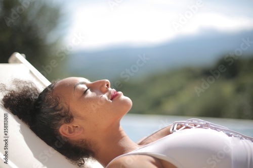 Closeup of an African woman peacefully relaxing by the pool under the sun