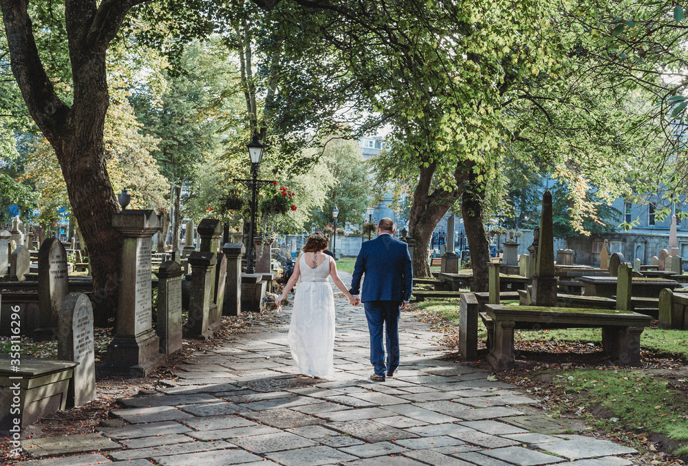 Newly married couple walk away in a cemetary Newly married couple walk away in a cemetary