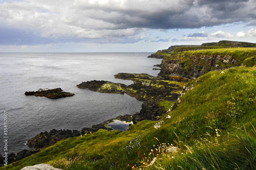 Vue sur les falaises vertes et les rochers du bord de mer, au soleil couchant en Irlande du nord.
