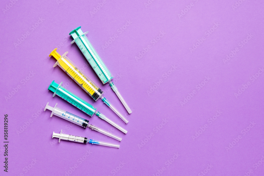 Top view of different syringes at purple background. Medical injection concept with copy space Top view of different syringes at purple background. Medical injection concept with copy space