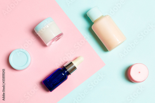 Top view of cosmetic containers, sprays, jars and bottles on pink background. Close-up view with empty space for your design