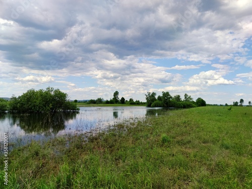 beautiful blue sky with clouds over a green field with a small river