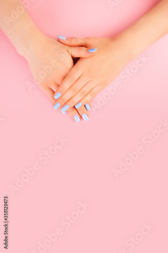 Hands of a beautiful woman on a pink background. Delicate hands with natural manicure  clean skin. Light blue nails.