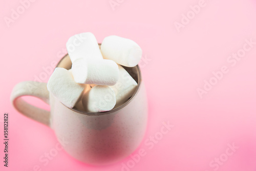 Marshmallows close-up and copy space on a pink background. Marshmallows in an earthenware mug.