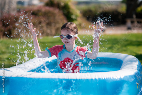 Tableau sur toile Little girl has fun splashing in paddling pool in summer