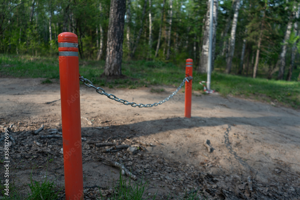 Orange posts with a chain on the lock. Obstruction for the passage of cars.