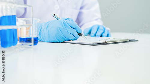 Medical or scientific researcher or man doctor looking at a test tube of clear solution in a laboratory photo