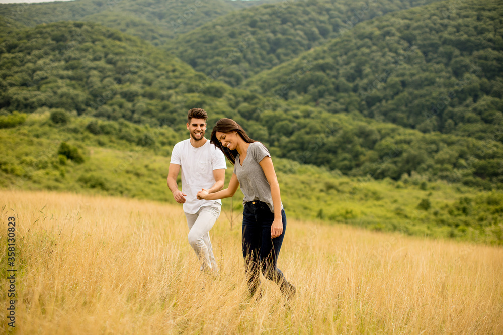 Happy young couple in love walking through grass field