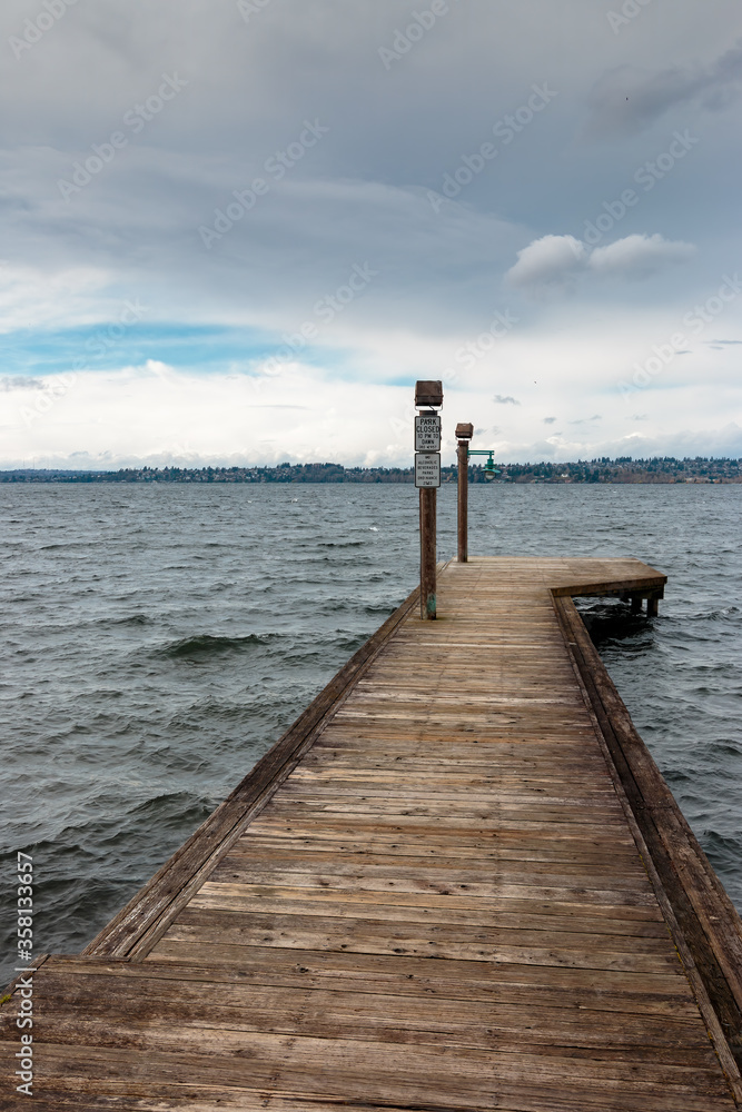 Receeding old wooden pier on Lake Washington with grey sky and waves Kirkland WA
