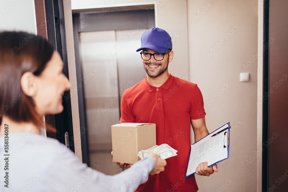 Beautifl woman moving into new apartment. Delievery man giving a package to a woman. Beautifl woman moving into new apartment. Delievery man giving a package to a woman.