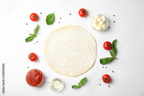 Flat lay composition with dough and fresh ingredients for pizza on white background