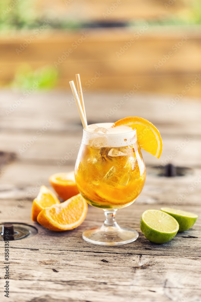 Fototapeta premium Beer lemonade in a glass with freshly cut orange, ice and paper straws
