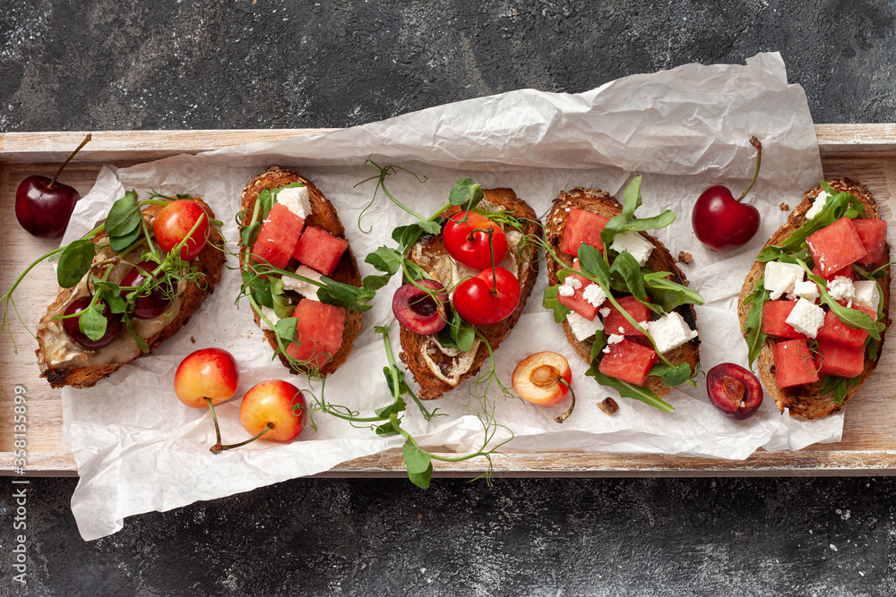 Fotografie Delicious healthy breakfast, fruit sandwiches with cheese, watermelon, cherries and herbs