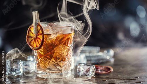 Bilde på lerret Smoked old fashioned rum cocktail with cubes of ice around on a dark background