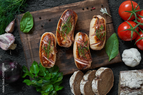 Obraz na płótnie grilled sausages with tomatoes and herbs on the board on a wooden table w salonie