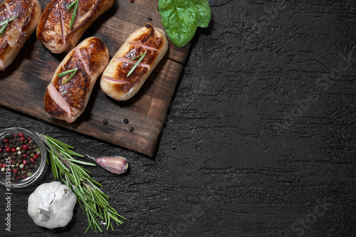 Obraz na płótnie grilled sausages with herbs on the board on a wooden table with copy space w salonie