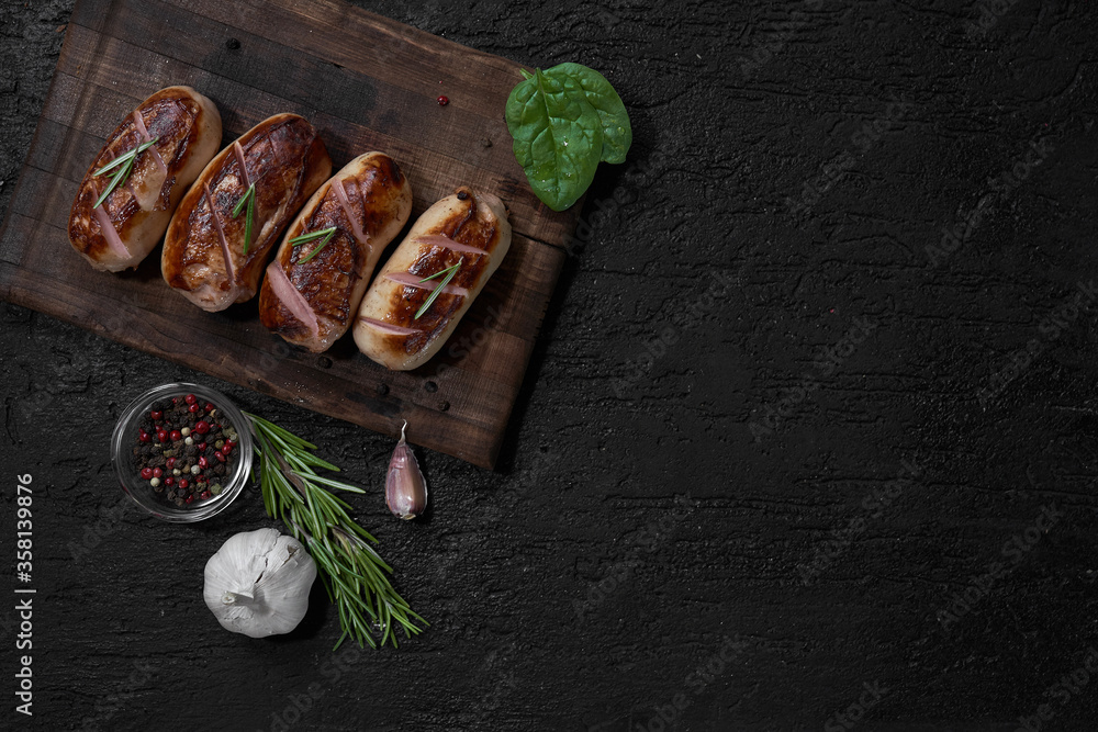grilled sausages with herbs on the board on a wooden table with copy space