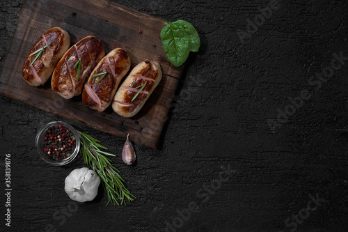 Obraz na płótnie grilled sausages with herbs on the board on a wooden table with copy space w salonie