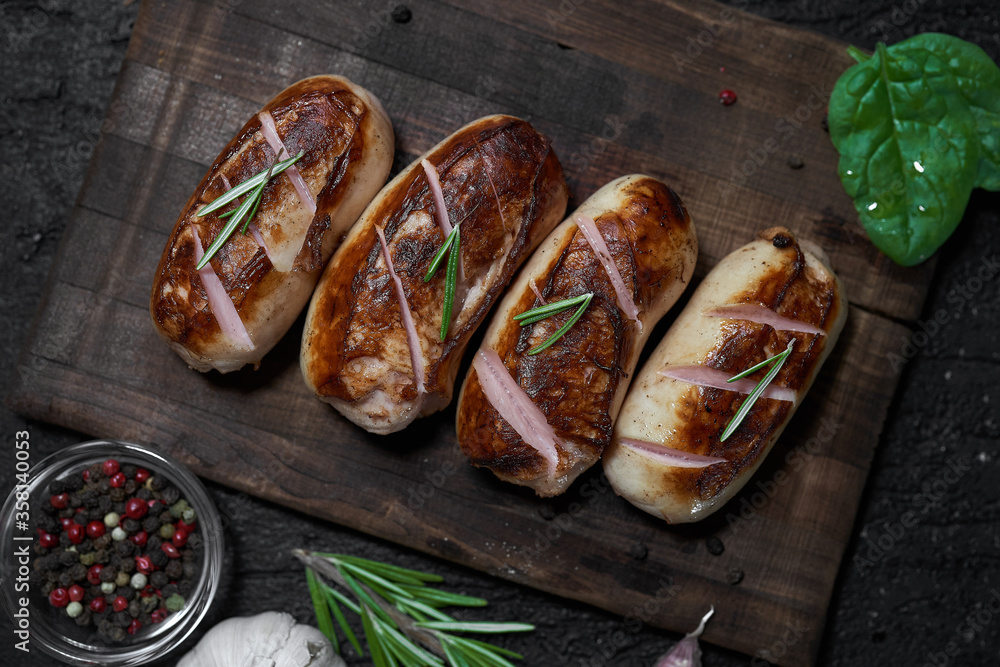 grilled sausages with herbs on the board on a wooden table with copy space