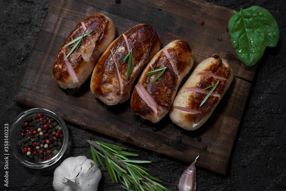 grilled sausages with herbs on the board on a wooden table with copy space