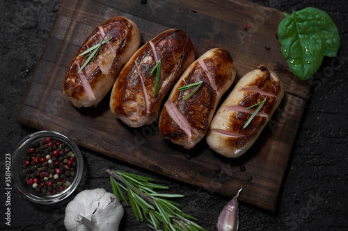 Obraz na płótnie grilled sausages with herbs on the board on a wooden table with copy space w salonie