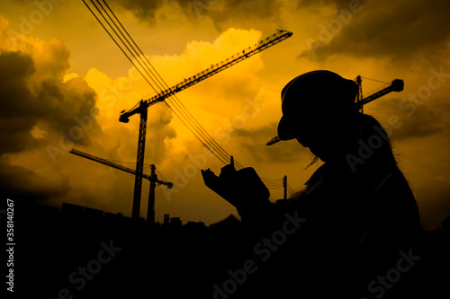 Silhouette Asian engineer working at site of a large building project,Thailand people,Work overtime at construction site
