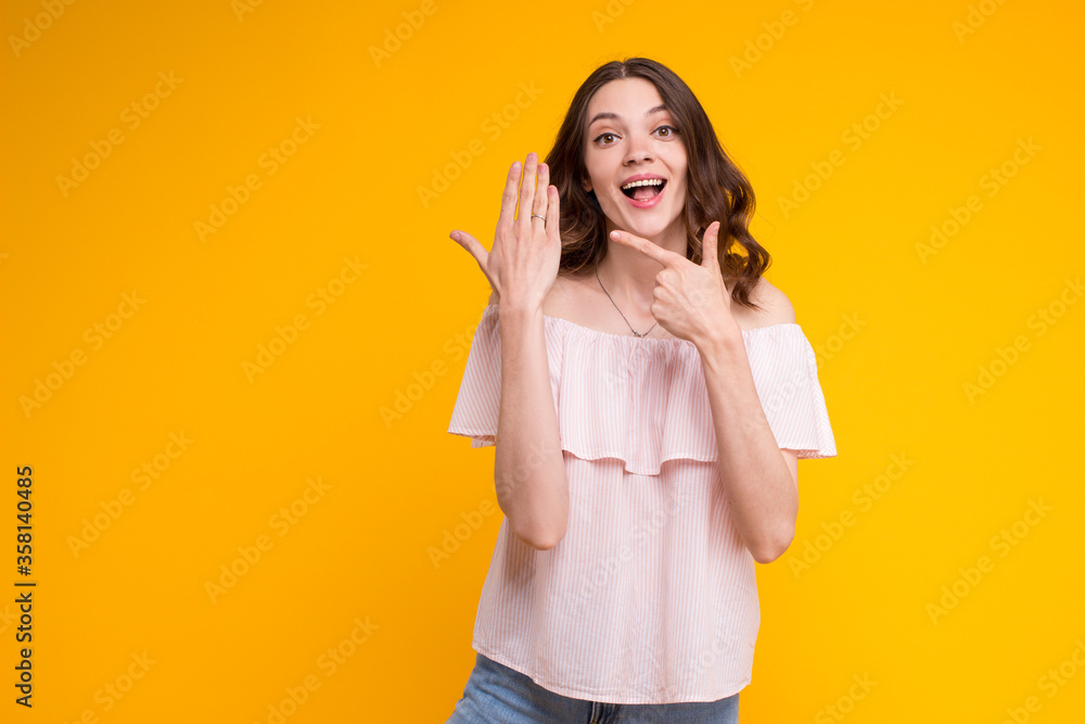 Beautiful excited young brunette woman showing pointing on engagement wedding ring on her finger,wearing summer stylish blouse,standing isolated on yellow background.I'm sorry I'm actually married Beautiful excited young brunette woman showing pointing on engagement wedding ring on her finger,wearing summer stylish blouse,standing isolated on yellow background.I'm sorry I'm actually married